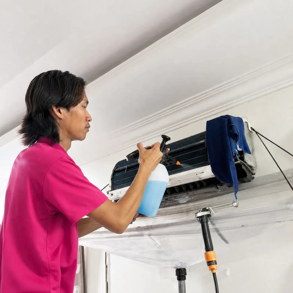 GenPlus technician cleaning an indoor split air-conditioner unit
