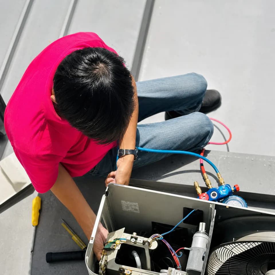 GenPlus technician using a manifold gauge to diagnose an aircond system