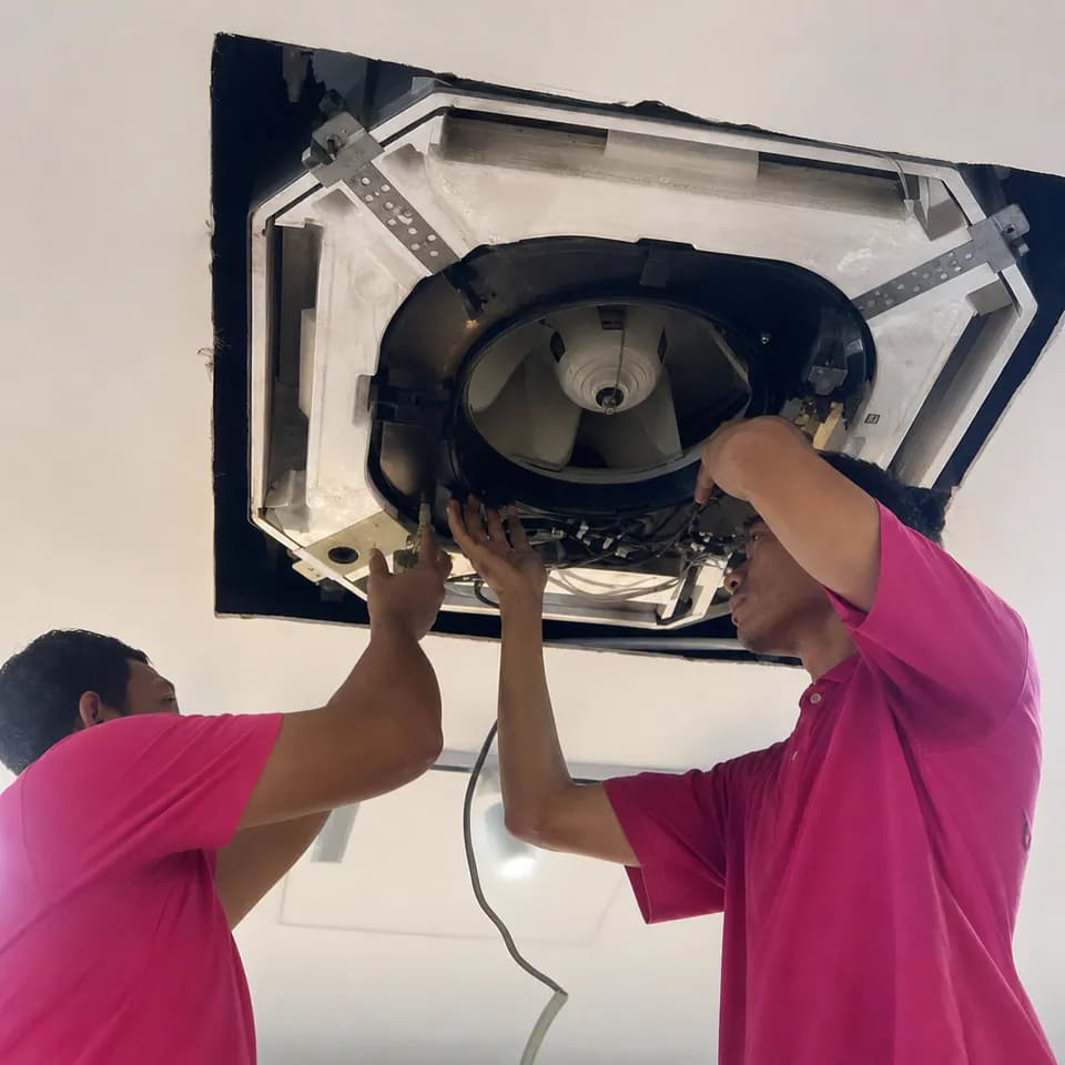 Two GenPlus technicians inspecting a ceiling-mounted air conditioning system