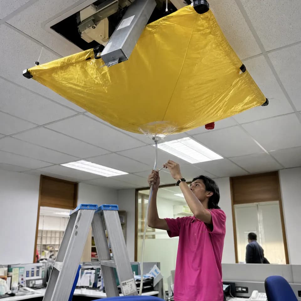 GenPlus technician servicing a ceiling cassette air conditioner in an office