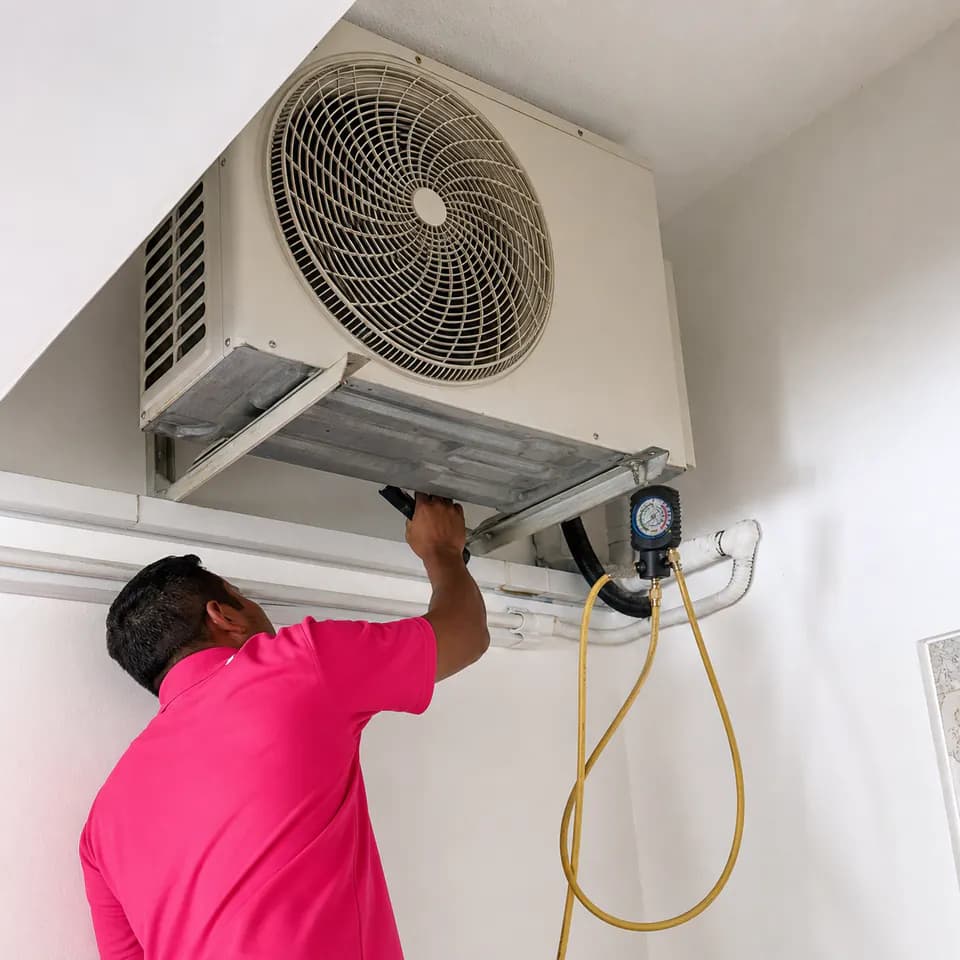GenPlus technician checking a wall-mounted outdoor condenser unit