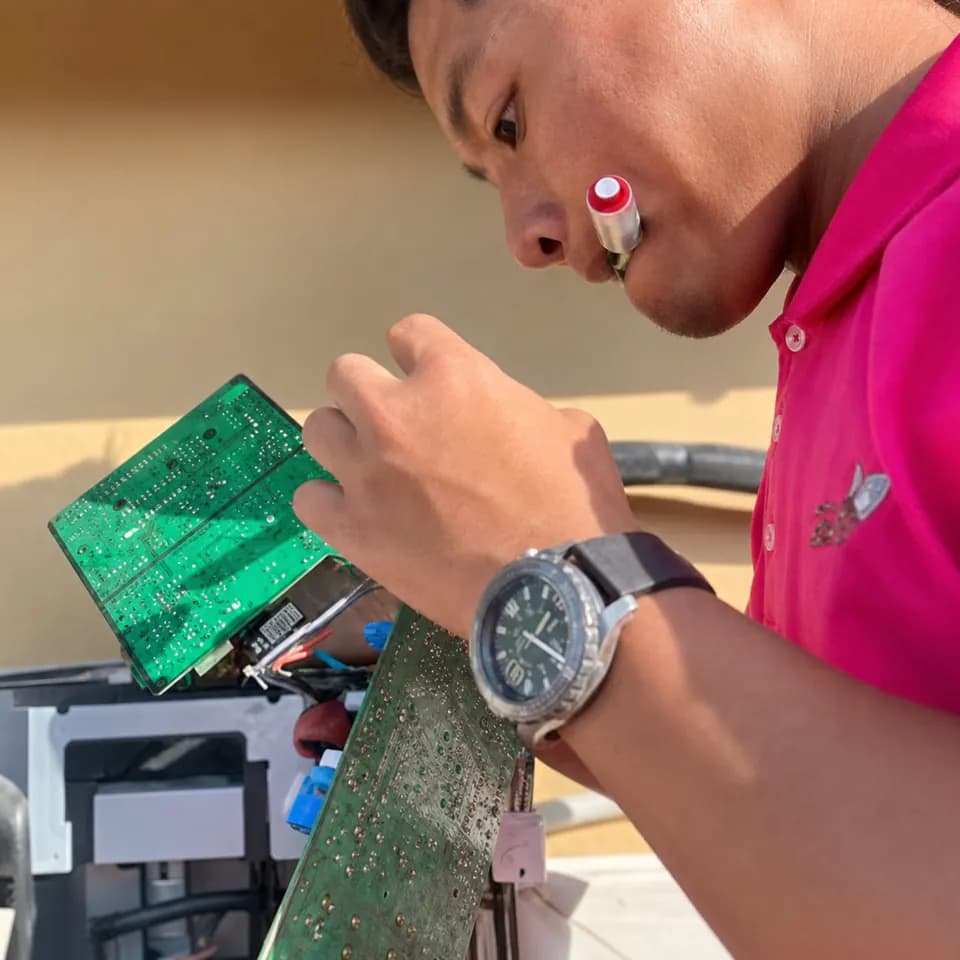GenPlus technician examining an air-conditioner circuit board